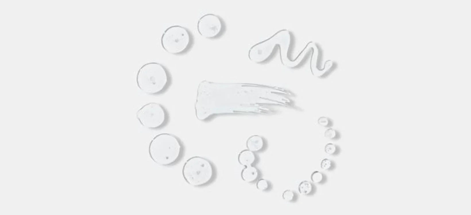 Clear skincare serums and creams arranged in artistic swirls, highlighting hydrating textures ideal for enhancing LED therapy treatments.