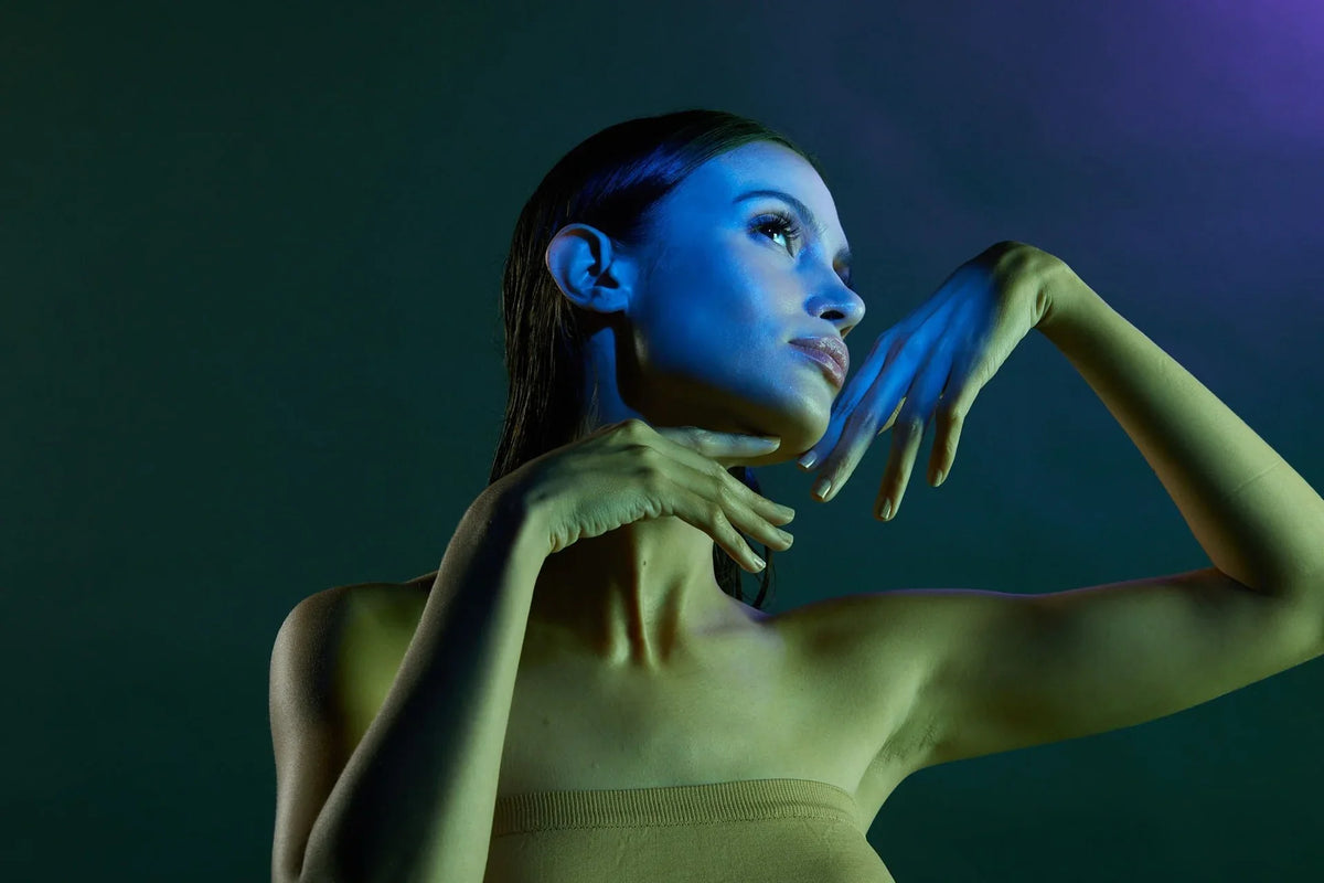 Model posing under blue and green LED light for skincare therapy, highlighting innovative skin treatment methods for 2024 glow-up.